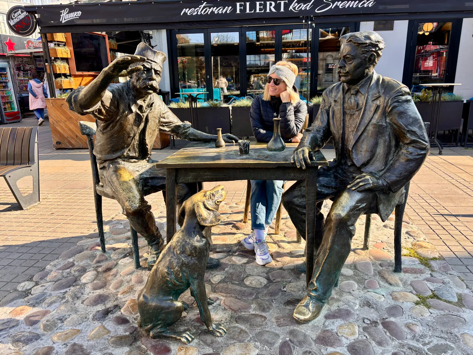 Aleks sitting with 2 old men and a dog (statues)